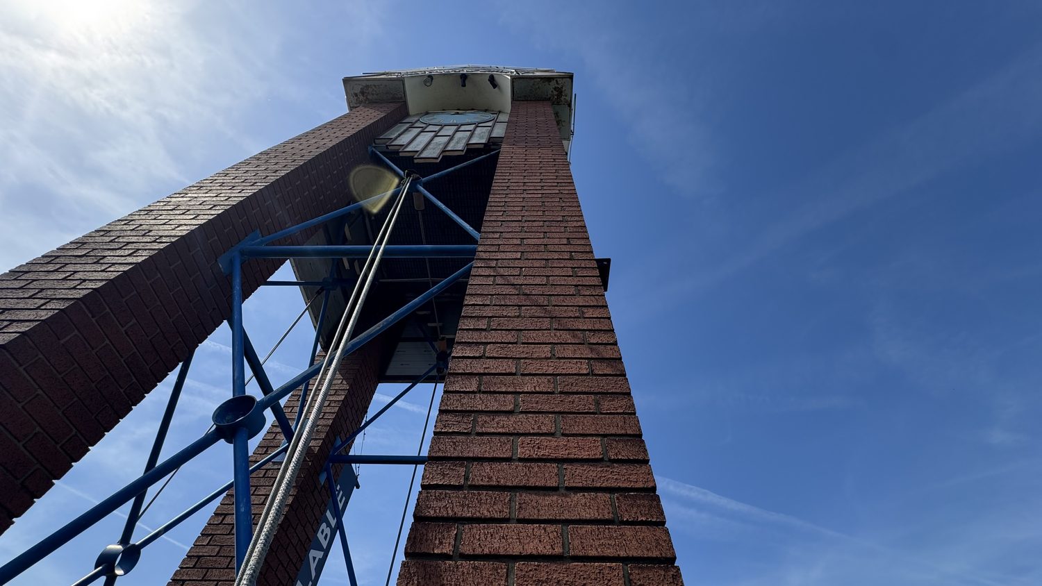 Brick clock tower with blue structural steelwork at Trinity Business Park, Chingford, viewed from the base