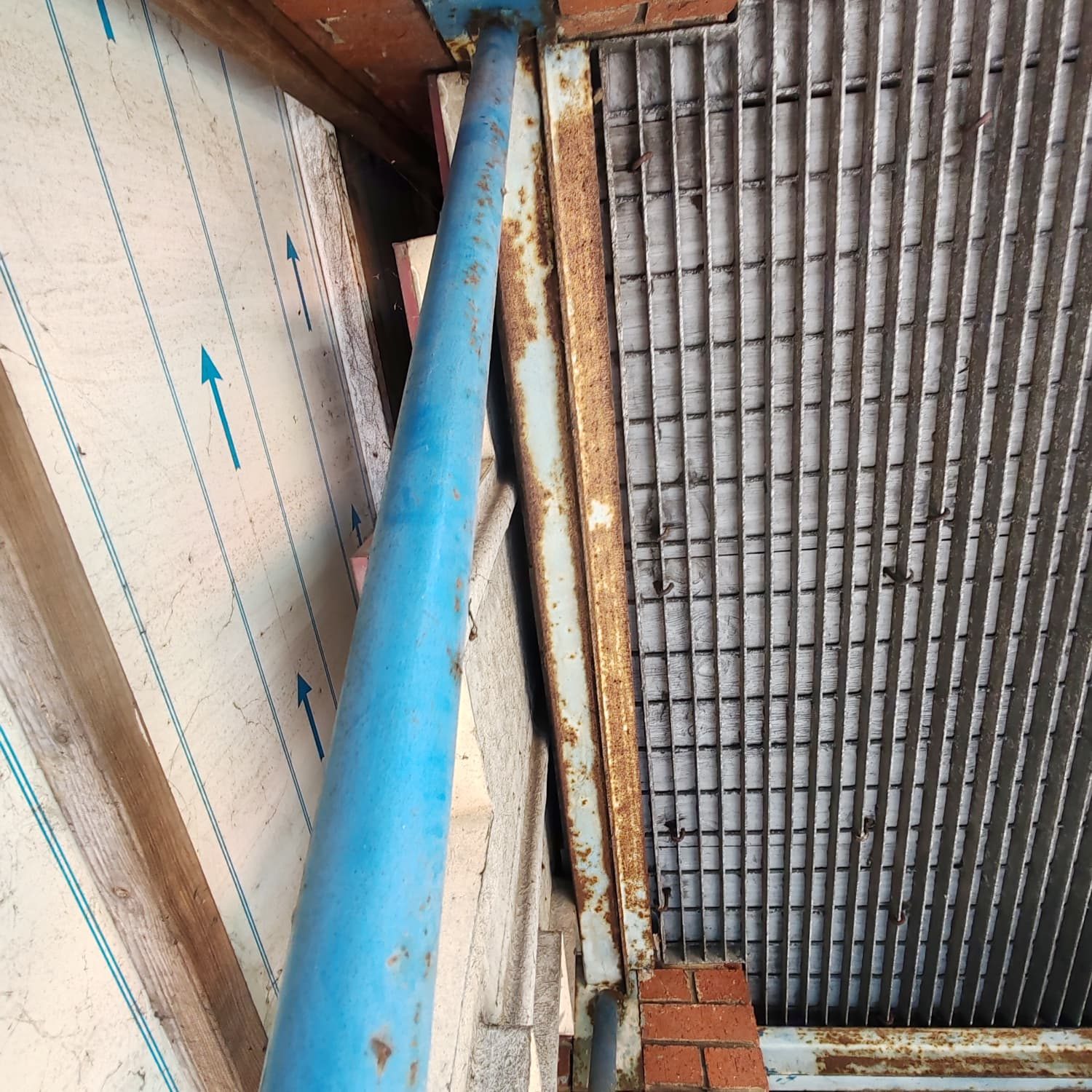 Corroded structural steel channel concealed behind the cladding line of a building elevation